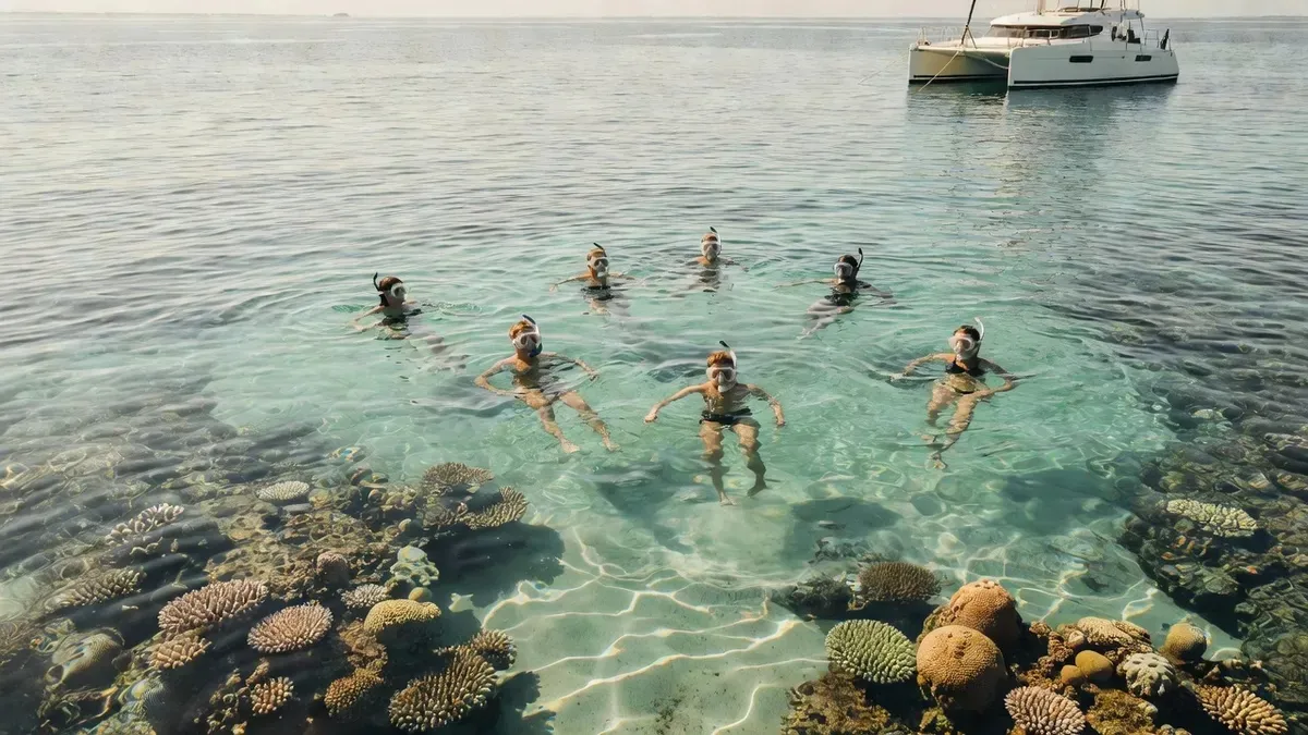 Snorkelers in clear turquoise water beside a catamaran on a Sint Maarten boat tour to the Prickly Pear Cays in Sint Maarten
