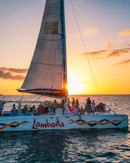 Sailing catamaran on a sunset Sint Maarten boat tour off Simpson Bay with the sky glowing orange over the Caribbean