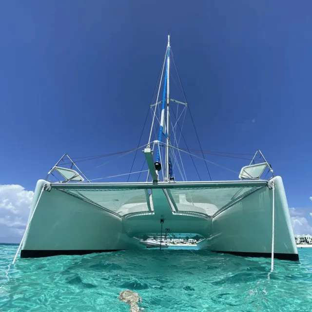 Snorkelers swimming beside a catamaran on a Sint Maarten boat tour with open bar over a clear turquoise bay off Saint-Martin