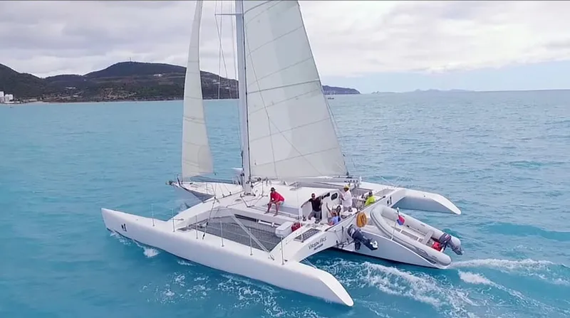 Sailing trimaran on a sunset Sint Maarten boat tour gliding along the west coast with golden light on the sails