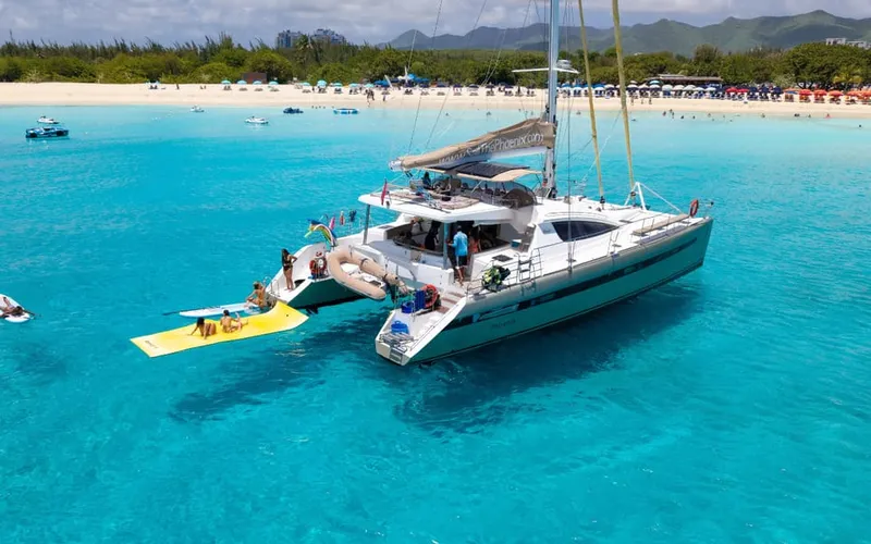 Luxury 62-foot catamaran on a Sint Maarten boat tour anchored in a calm turquoise bay with guests relaxing on the wide deck